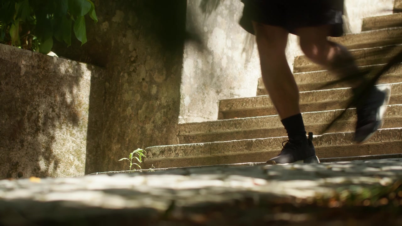 A close-up shot of a man’s foot as he walks down the stairs in Coimbra’s Botanical Garden, capturing the details of the natural surroundings
