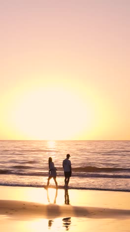 couple walking on the beach at sunset