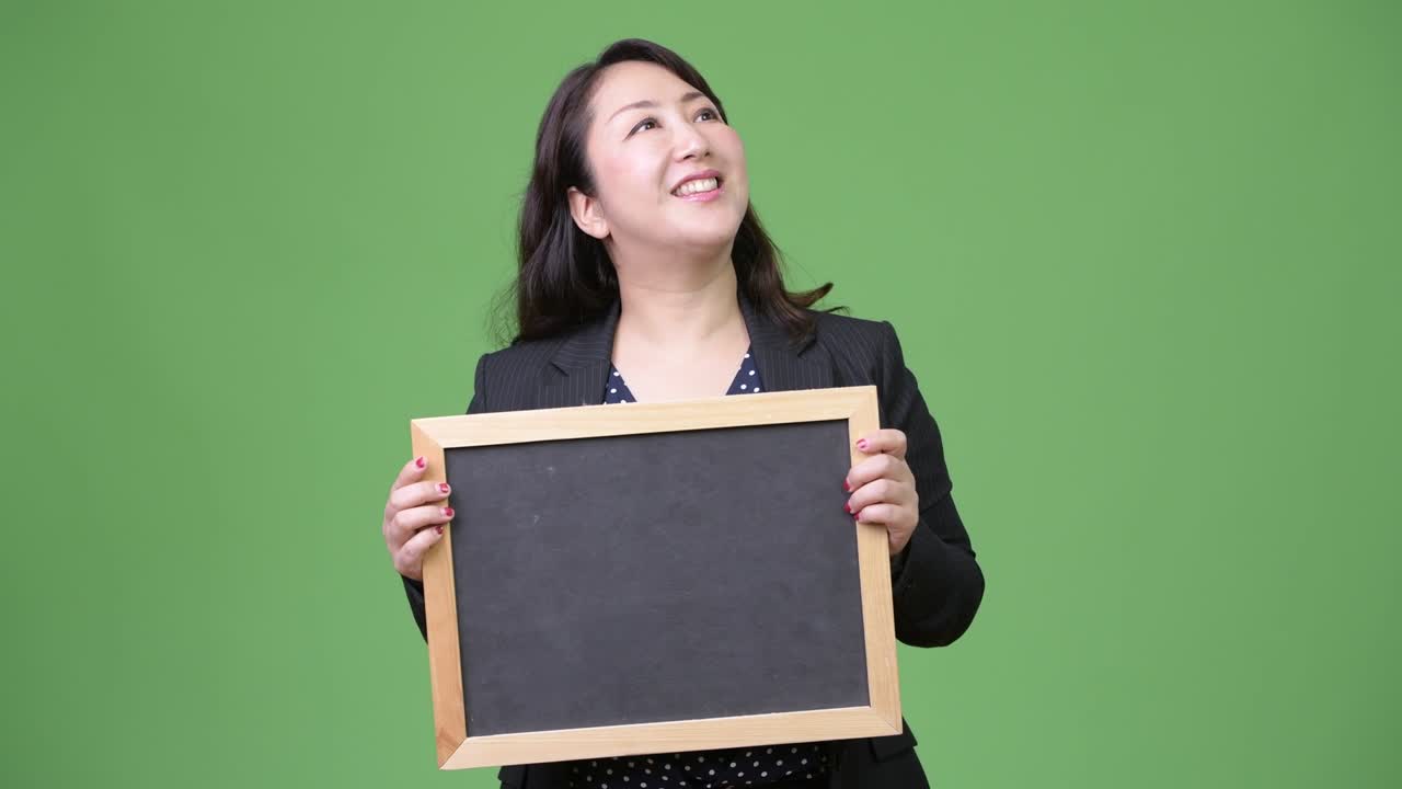 성숙한 아름다운 아시아 사업가 여성은 블랙보드 보여주는 동안 생각