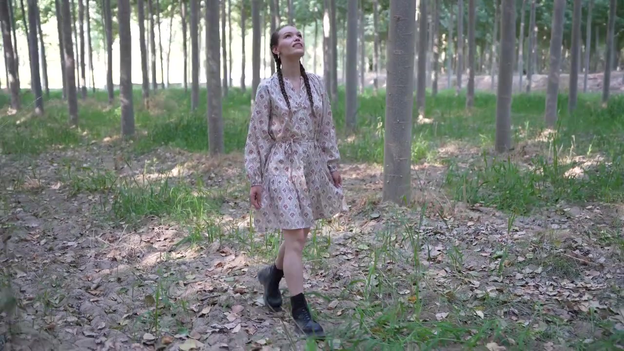 Una giovane donna passeggia in una lussureggiante foresta verde mentre la luce del sole filtra dolcemente tra gli alberi.