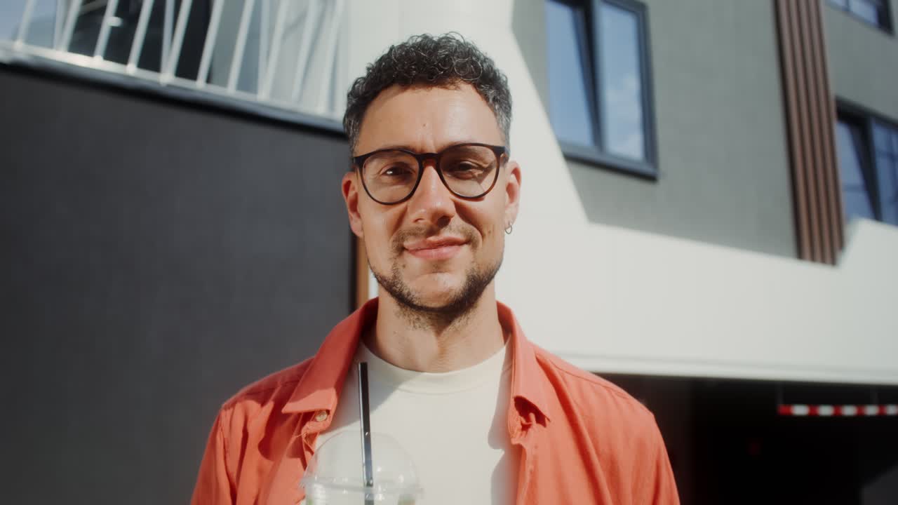 hombre disfrutando de una bebida frente a un edificio moderno