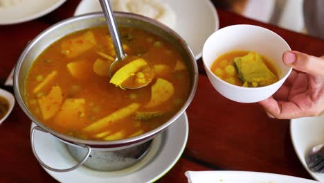 ladling soup into a bowl at a table