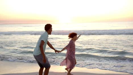 Una-Pareja-Birracial-Disfruta-De-Un-Momento-Lúdico-En-La-Playa-Al-Atardecer