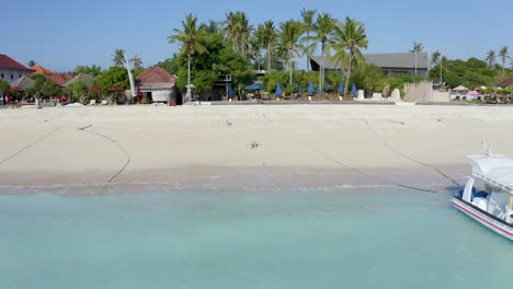 drone footage of sandy beach and turquoise ocean while beautiful sexy woman sleeping on the beach