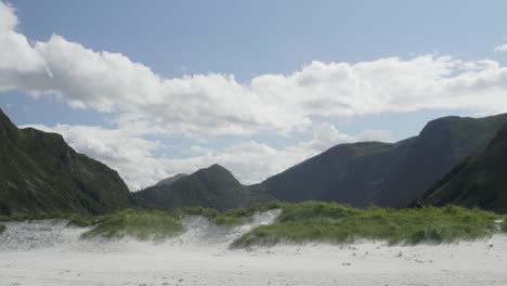 Radreisender-Radfahrer,-Der-Von-Rechts-Nach-Links-Durch-Einen-Extrem-Breiten-Rahmen-Aus-Wunderschönen-Berg--Und-Strandlandschaften-Fährt