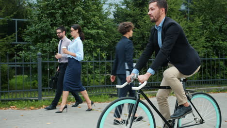 businessman riding bike with colleagues walking