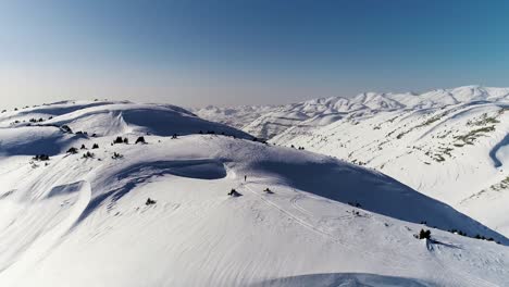 sensational flight above white snow covered akoura mountain ridge towards bright blue sky and range, lebanon, overhead aerial approach