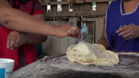 mexican cooks flipping a tlayuda on a comal