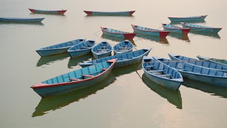 colourful tourist boat trip rowing boats on phewa lake in pokhara at sunset in nepal, beautiful fewa lake with amazing dramatic mountain scenery in pokhara