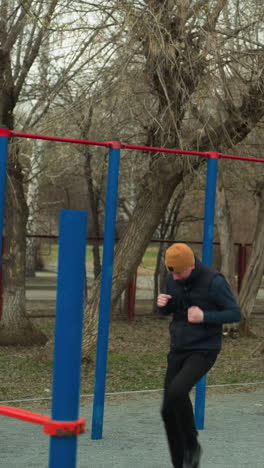 un entrenador corre rápidamente en un estadio, rodeado de postes azules y rojos, con un banco cerca, con una vista borrosa de un coche blanco pasando con su farol