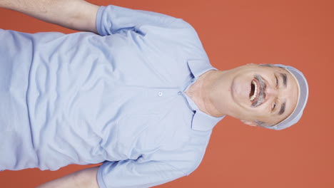 Vertical-video-of-Old-man-making-heart-sign-at-camera.