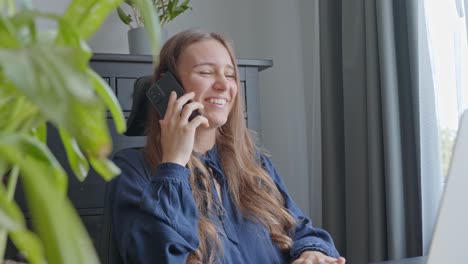 Mujer-Joven-En-Una-Pequeña-Oficina,-Hablando-Por-Teléfono,-Riendo-Y-Sonriendo,-En-Cámara-Lenta