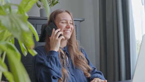 mujer joven en una pequeña oficina, hablando por teléfono, riendo y sonriendo, en cámara lenta
