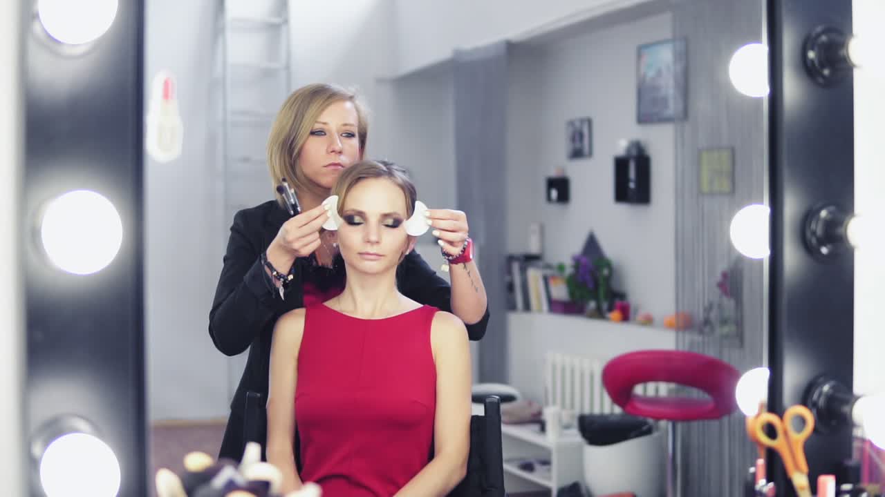 Makeup artist removing white patches for skin protection from model's skin. Professional makeup. Slow Motion shot