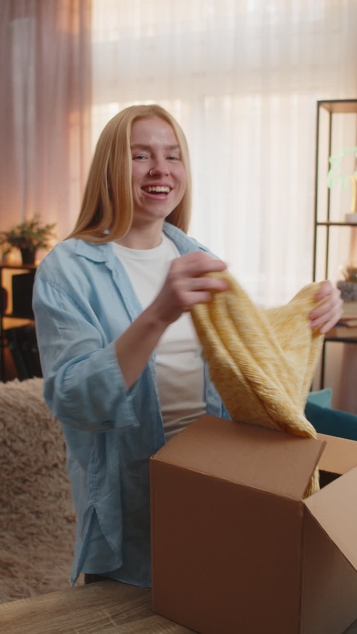 mujer joven desembalaje paquete en casa feliz encontrar sofá revelar exhibición sonriente descubrimiento casual