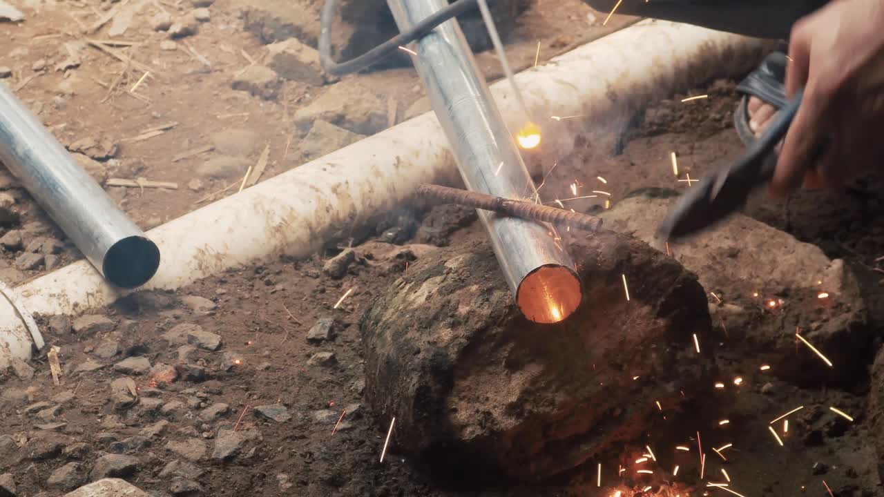 soldador profesional que emplea una máquina de soldadura industrial para unir dos piezas de metal creando una estructura metálica como parte de su trabajo diario en una pequeña empresa local