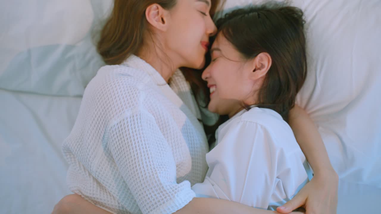 침대에 누워 있는 두 여인, 애정을 나타내고