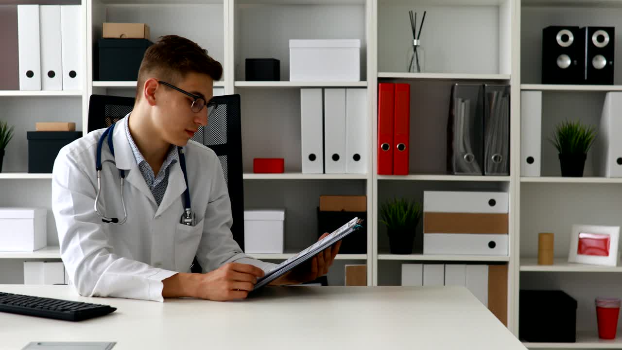 紙を見せてカメラを見ている若い医者