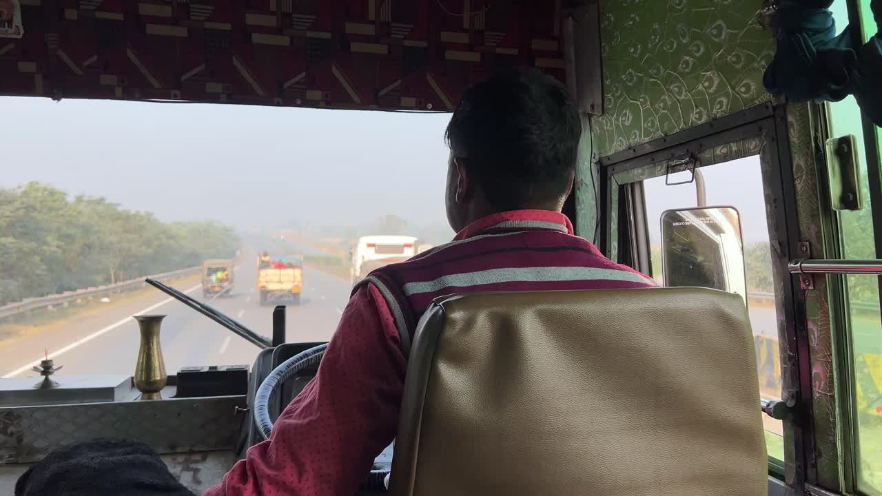 Back view of Bus driver driving by handling steering wheel. Highway driving.