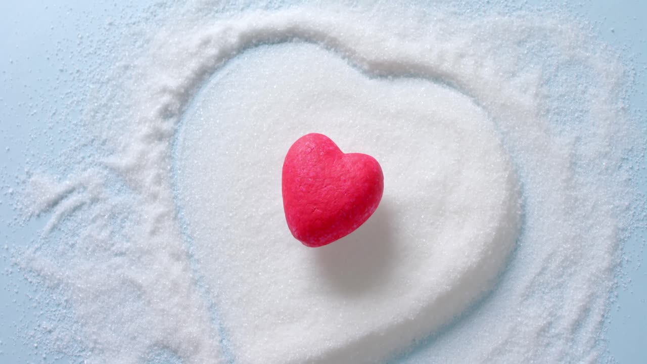파란색 배경에 심장 모양의 설탕 위에 빨간 심장의 클로즈업, 느린 동작