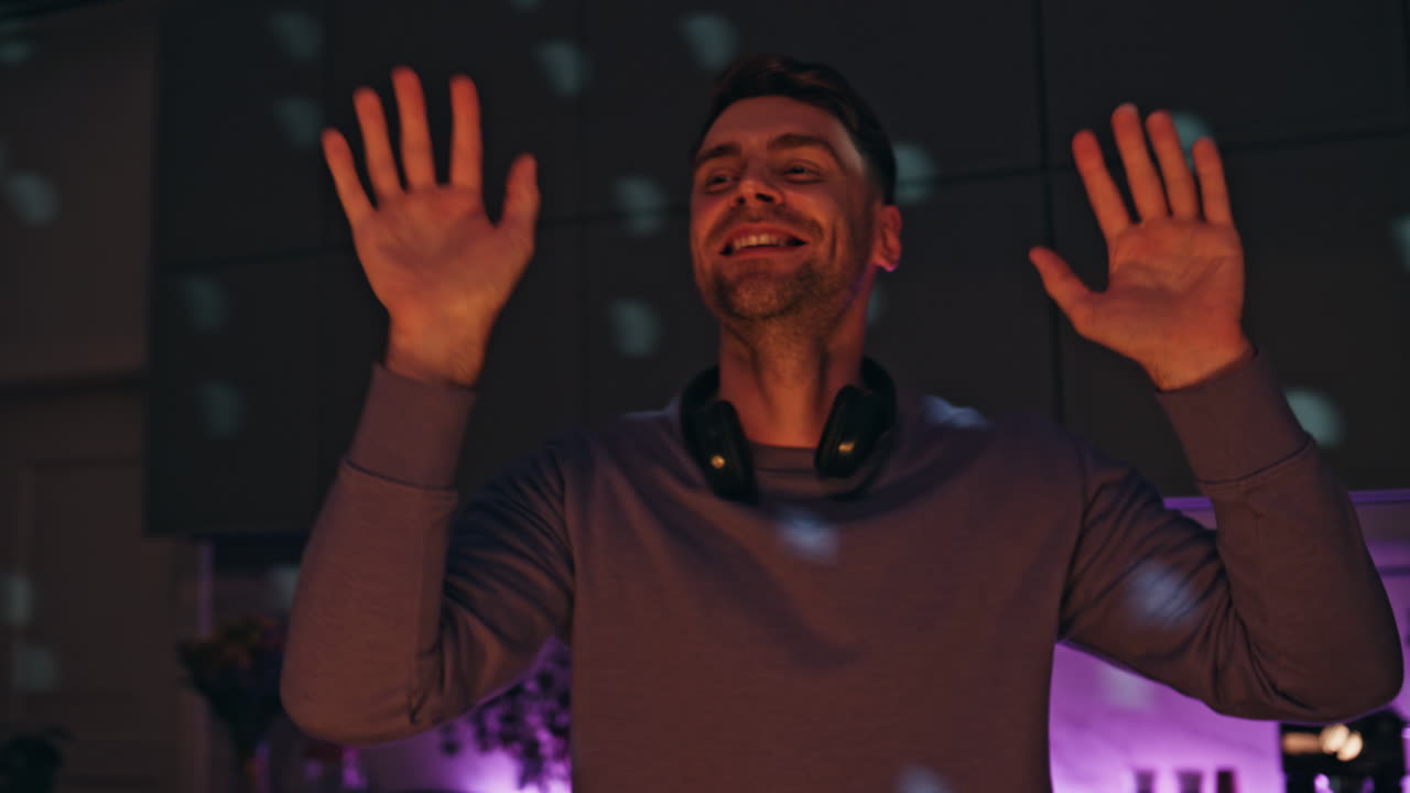 Happy dj dancing disco party with headphones on neck close up. Man clapping