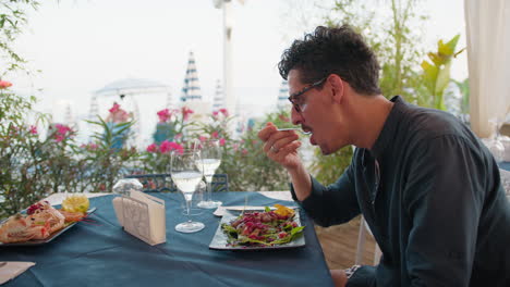 man admiring the sea landscape while eating lunch at the beach resort