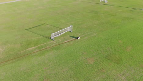 a remote-controlled robot paints precise lines on a soccer field under bright daylight, showcasing automation in sports field maintenance