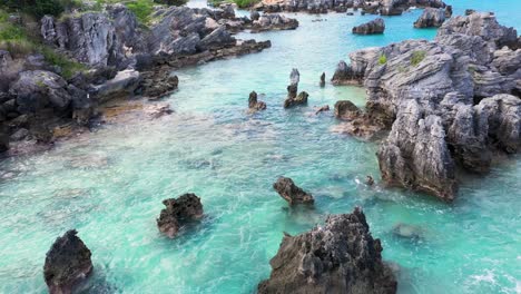 aerial view of sharp pointy rocks in turquoise water by tropical island