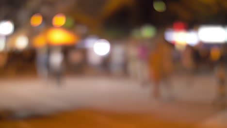 illuminated night street with walking people defocus