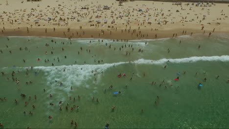 toma de drones de una gran multitud nadando en la playa de bondi a mediados de verano en un día caluroso y claro