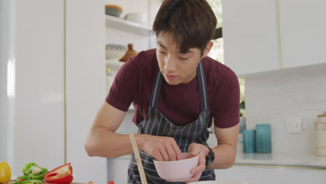 asian boy wearing apron preparing food in the kitchen at home