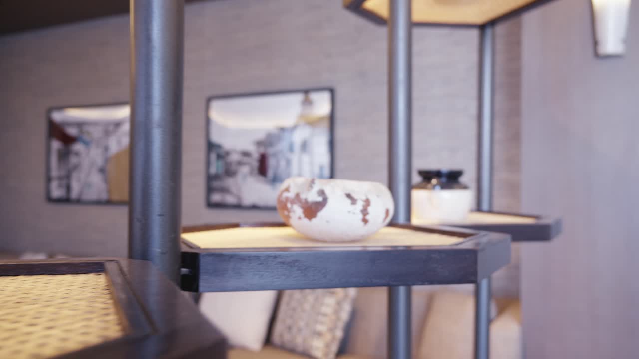 Tracking shot of various ceramic vases and traditional pottery exhibited on minimalist dark wood and cane pedestals within a luxury lounge