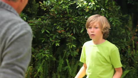 Boy-playing-with-baseball-with-father-in-garden