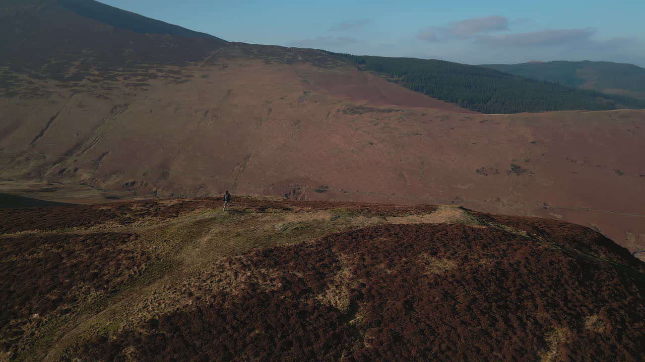 excursionista en la cima de una colina con revelación de órbita de misty mountains con destello de lente natural en barrow cayó english lake district uk