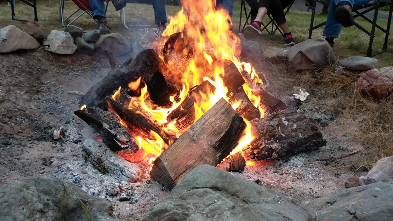 People sitting around camp fire in 4k