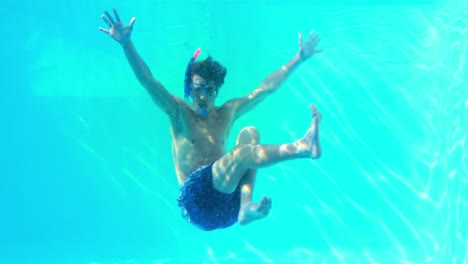 hombre en snorkel saltando en la piscina saludando a la cámara