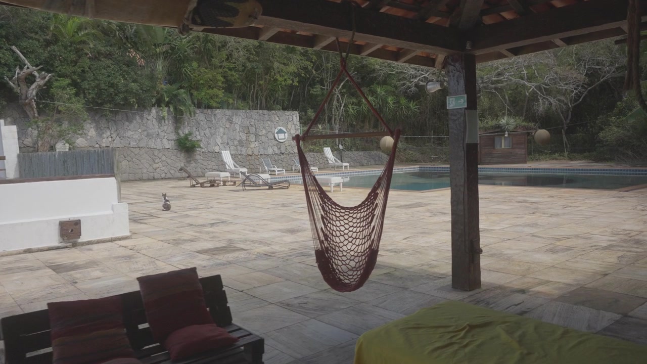 Una sedia amaca sospesa sotto un pergolato accanto a una piscina tranquilla.