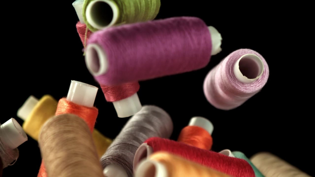 Colorful Sewing Threads Falling in Slow Motion on Black Background