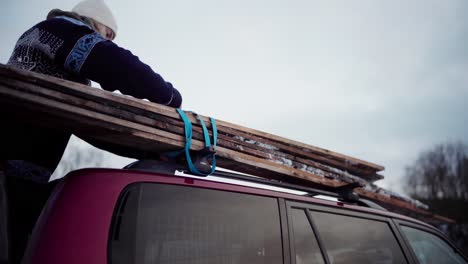 The-Man-is-Loading-the-Gathered-Planks-of-Wood-Onto-the-Roof-of-His-Car-in-Indre-Fosen,-Trondelag-County,-Norway---Close-Up