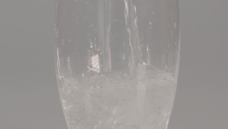 tilt up of sparkling water being poured into glass against a white studio background