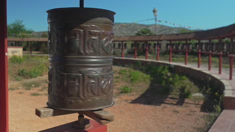 Buddhist-prayer-wheel-spins-peacefully-in-a-sunny-hilltop-garden-on-a-clear-day