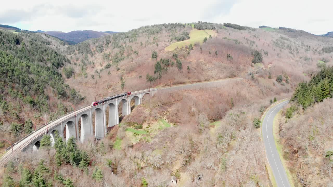 Aerial View of Train on Viaduct Through Mountainous Landscape