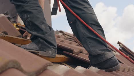 close up to a worker walking on rooftop, roof tile removal