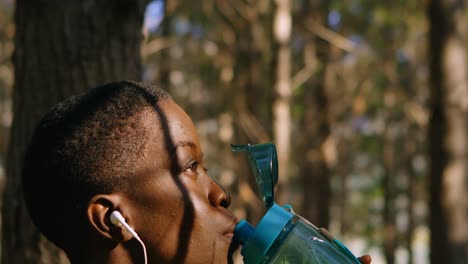 female jogger drinking water in the forest 4k