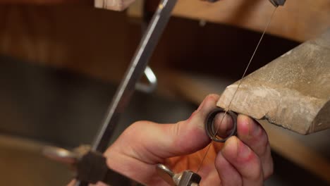 a gold ring in the making by a jeweller sawing the pieces