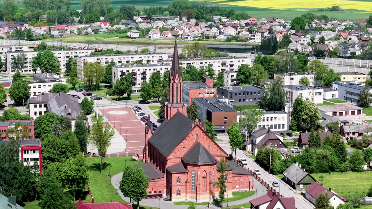 Betagende luftoptagelser af Kaišiadorys Katedral i Litauen, der viser dens slående røde murstensarkitektur, frodige grønne områder og livlige by under skarpt dagslys. Luftdronevideo.
