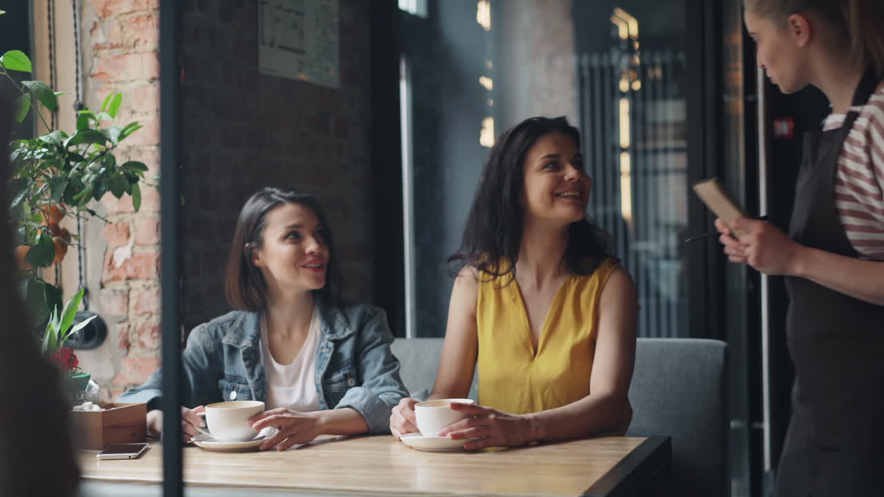 Women enjoying coffee and chatting with waitress