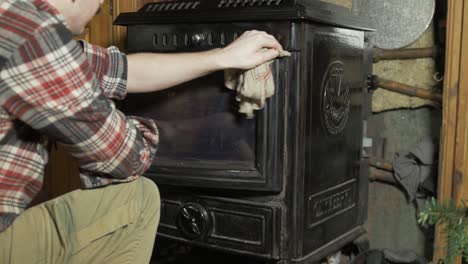 joven limpiando el polvo de la estufa de combustible sólido