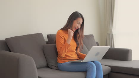 Schlanke,-Erfolgreiche-Asiatin-In-Einem-Orangefarbenen-Rollkragenpullover,-Die-Am-Laptop-Arbeitet