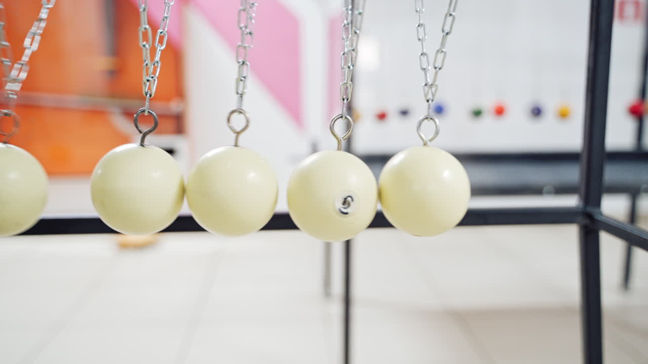 Hand holding a pendulum ball. Newton's cradle